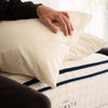 Person adjusting pillows on a mattress labeled 'The Ultimate Snooze'. made with organic cotton and wool for an organic toxin free pillow by The Ultimate Snooze